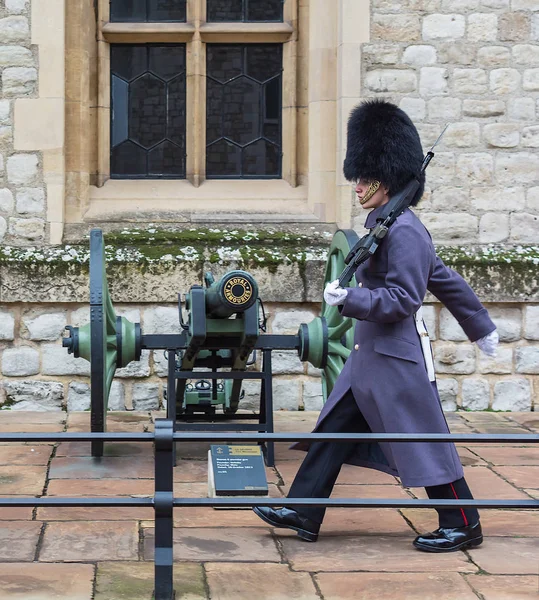Tower of London, London, Büyük Britanya - 24 Kasım 2018: Kraliyet muhafızı. Genç asker yürüyüşleri yakınındaki bir silah