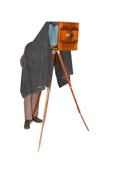 Fotoğrafçı bir tripod üzerinde vintage ahşap plaka foto kamera ile fotoğraf çekmek. Beyaz arka planda yalıtılmış Stok Resim