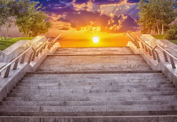 granite staircase with handrails in the city and beautiful evening sky with sun