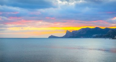 Deniz Bay renkli gün batımı. Dağlık arka plan.