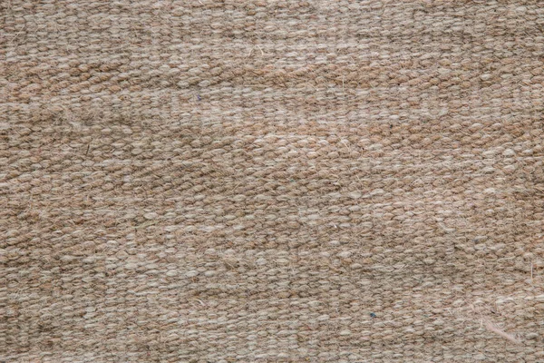 Woolen knitted carpet of rough weaving. Close-up. Background.