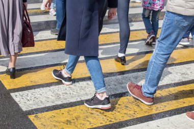 people passing on the road at a pedestrian crossing. Close-up, legs clipart
