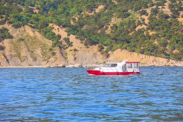 Barca si muove sul mare lungo le rive montuose — Foto Stock