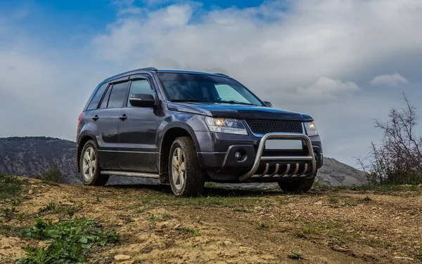 SUV on the field under a cloudy sky. — Stock Photo, Image
