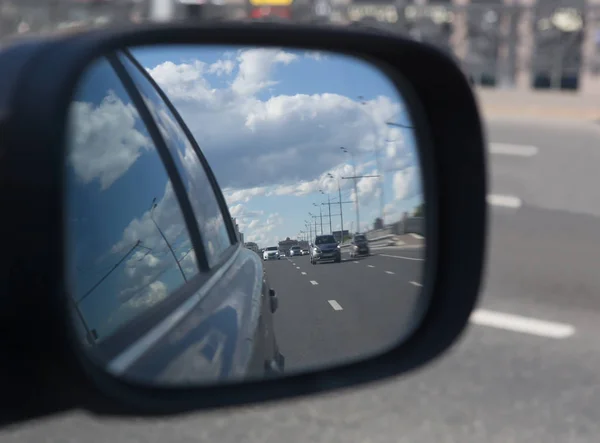 Отражение в зеркале заднего вида движущихся по дороге автомобилей — стоковое фото