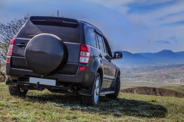 Bulutlu bir gökyüzü altında sahada SUV.