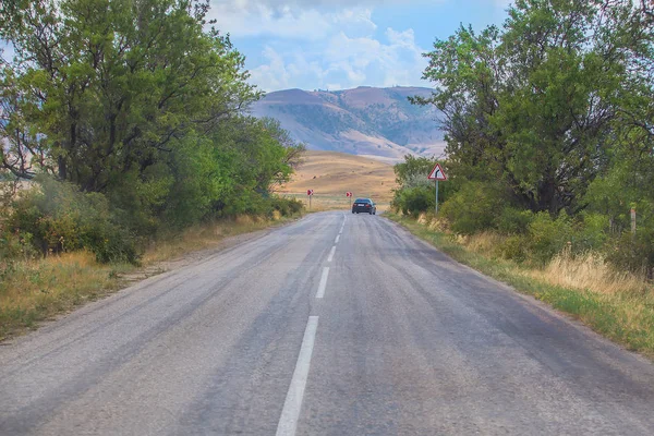 Coche Se mueve a lo largo de un camino sinuoso en las montañas durante —  Fotos de Stock