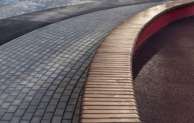 Oyun parkında uzun ahşap bir bank olan dolambaçlı kaldırım.