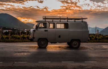 Minivan gün batımında bir köy yolunda gidiyor.