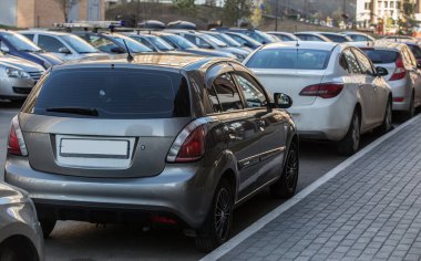 Bir apartmanın avlusunda kaldırıma park etmiş arabalar.
