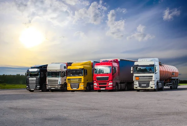 Yarı römorkörler park alanında gökyüzüne karşı arka arkaya geliyor.