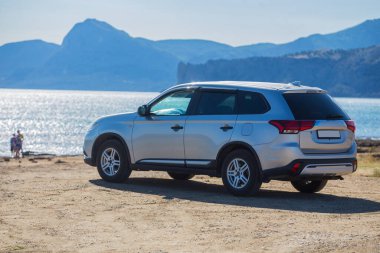 Dağların yakınındaki deniz kıyısında bir cip. Bir aileyle doğaya, denize arabayla gitmek..