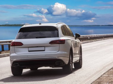 Güneşli bir günde, güzel bir gölün kıyısındaki otoyol boyunca ilerler.