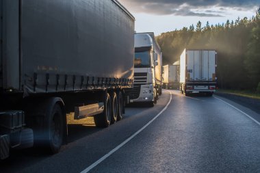 Kamyonlar şafak vakti banliyö otobanında zıt yönlere hareket ediyor.