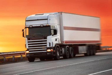 Kamyon gün batımında otoyola çıkıyor.