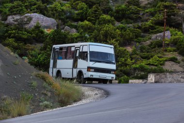 Otobüs dağlarda dolambaçlı bir dağ yolunda ilerliyor..
