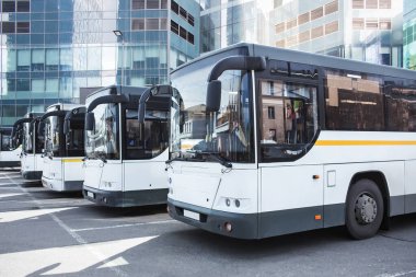 Şehirdeki otobüs durağında bir sürü turist otobüsü var.
