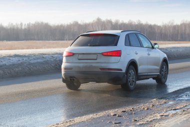 Araba ıslak ve kirli kır yolunda ilerliyor. Arka ve yan görünüm.