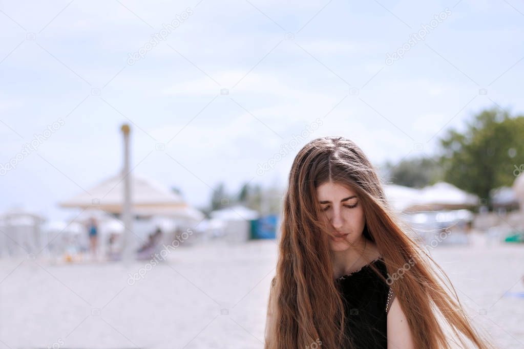girl with long brown hair sitting on the beach