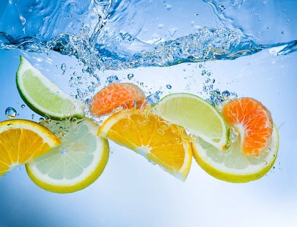Tropical fruits fall deeply under water with a big splash — Stock Photo, Image
