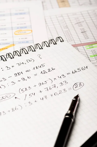 Notebook with financial records on the background of the table with the accounting calculations, vertically