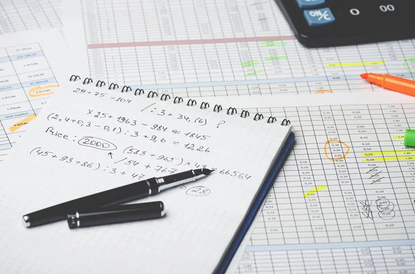 Kağıt defter ile muhasebe hesaplamalar ve kalem numaraları ile bir tablonun arka plan üzerinde