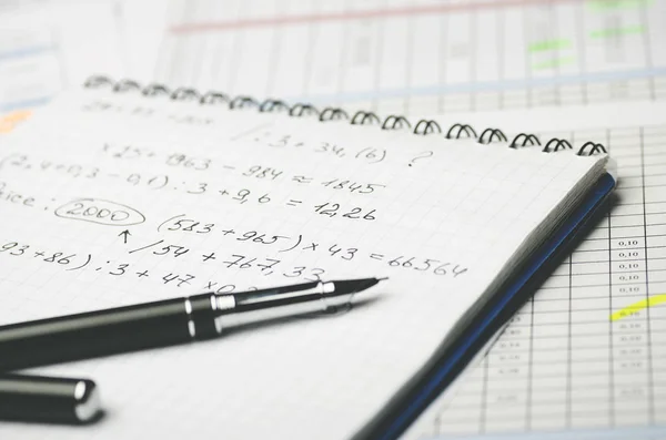 Kağıt defter ile muhasebe hesaplamalar ve tablonun arka plan üzerinde kalem