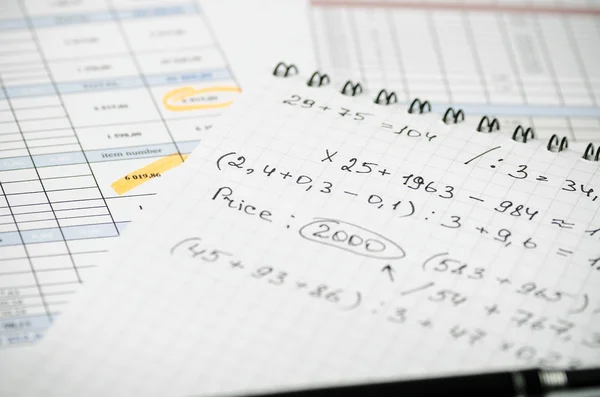 A paper notebook with financial records on the background of tables