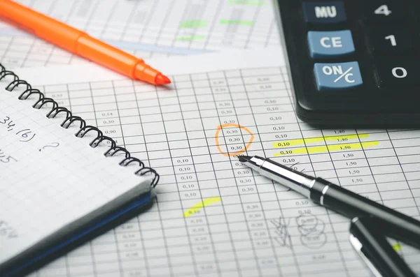 Kağıt üzerinde notlar, kağıt defter, hesap makinesi ve siyah kalem ile mali tablolar