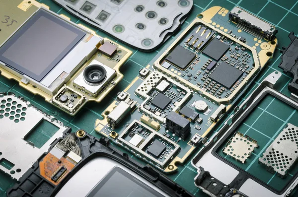Eski cep telefonu ile yarı iletken parçalar ve değerli metaller yakın çekim yeşil zemin üzerine elektronik parçalar