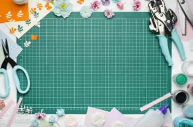 Kesme mat kağıt çiçek, kağıt, araçları ve scrapbooking malzemeler ile çevrilidir. Scrapbooking, üstten görünüm, ortasındaki boş alanı