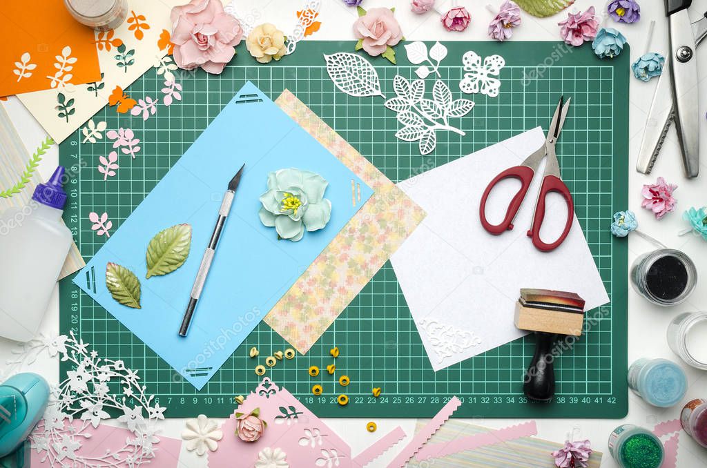 Multi-colored paper cards on the cutting mat, tools and materials for scrapbooking, top view