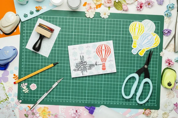 Çok renkli kağıt, ev yapımı kartpostal ve scrapbooking araç ve gereçleri yeşil hasır üzerinde kesme, üstten görünüm, ellerimi