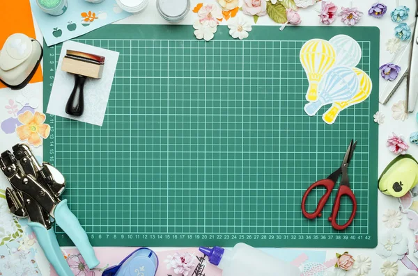 Çok renkli kağıt, scrapbooking araç ve gereçleri yeşil hasır üzerinde kesme, üstten görünüm, ellerimi