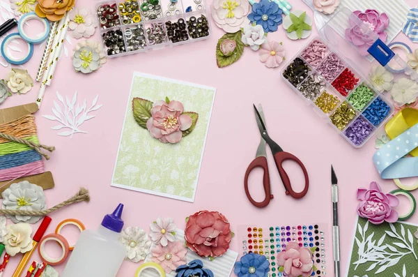 Kağıt çiçekler, makas, ev yapımı kart, kağıt ve pembe arka plan üzerinde scrapbooking öğeleri. Scrapbooking, üst görünüm