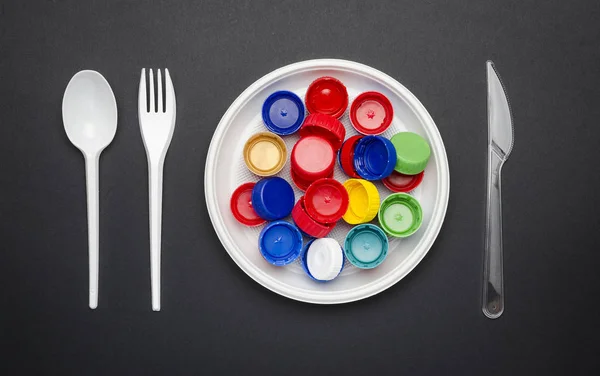Disposable plastic tableware with plastic lids, black background, top view