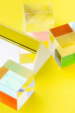 Sarı arka plan üzerinde parlak cam figürler, soyut, dikey