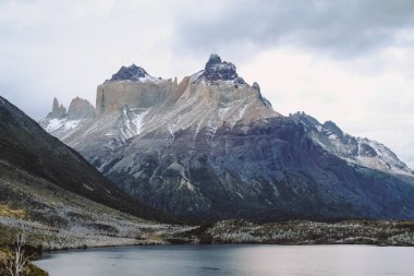 Şili. Torres del Paine. Dramatik manzara. Hızlı dağ nehir kayaların arasında karla kaplı dağlar arka planı geçiyor..