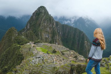 Sarışın kız gri kazak ve kot Machu Picchu, Peru, Ocak 2018. Dağlarda antik kenti