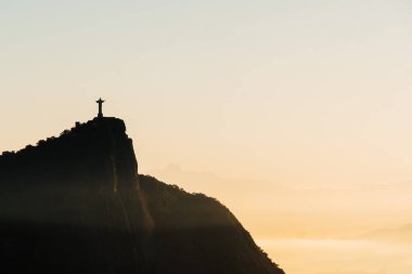 Brezilya, Rio de Janeiro. Şafak hill iki kardeş üzerinde toplantı. Büyük şehir, göl, okyanus, tepeler, dağlar manzarası. Uzakta tepedeki İsa heykeli turuncu renkler