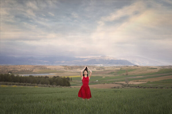 Girl in red dress in the field at sunset