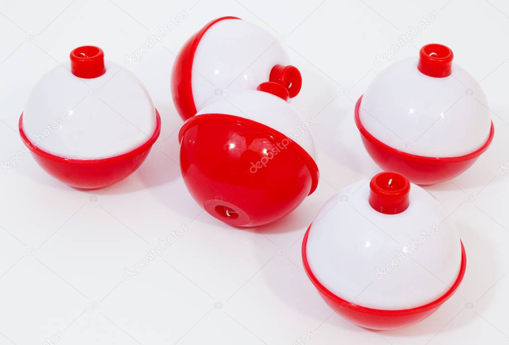 Red and white fishing bobbers on a white background.