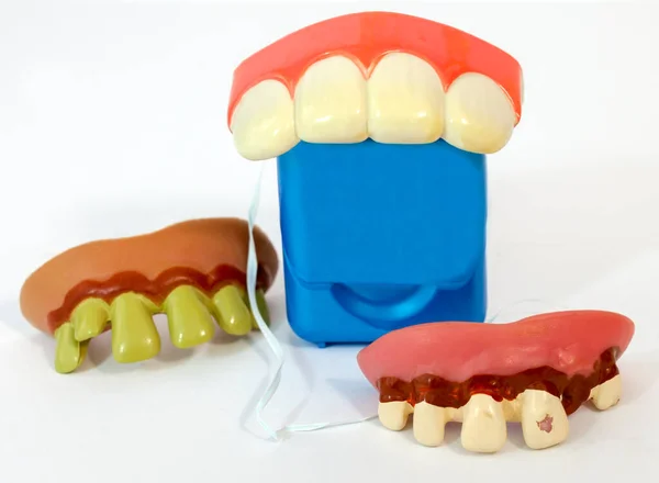 Humorous dental hygiene concept with ugly costume teeth and dental floss.