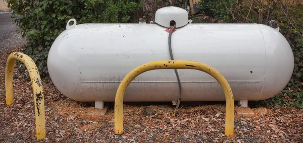 Large propane liquid gas tank protected with yellow metal bollards.