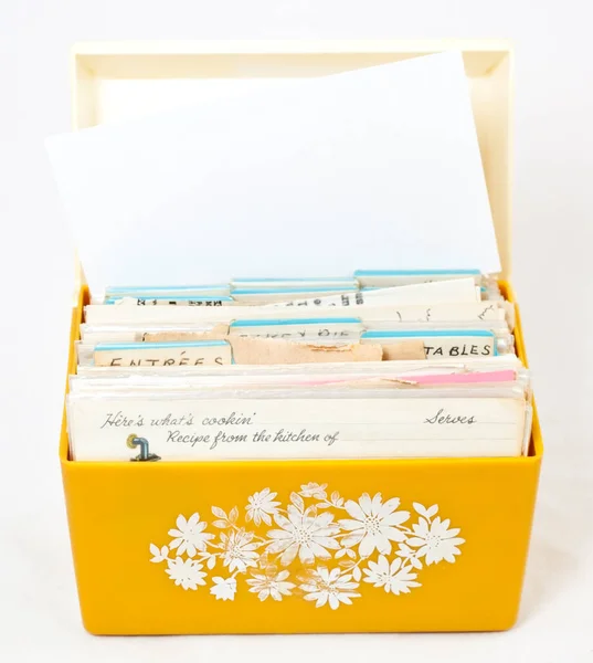 Open front view of vintage 1970s yellow recipe box with recipe cards. Isolated.