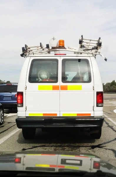 Rear view of parked utility maintenance van with yellow and orange day-glo alerts. Horizontal.