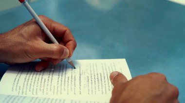 Bir kitabın üzerine yazan siyahi bir adamın ellerinin fotoğrafı.