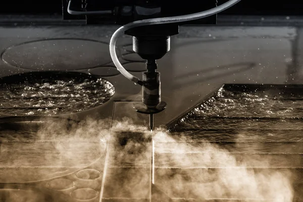 Close up of water jet cnc machine cutting steel with high water pressure for metalworking industry. Jet splash and drops flying.