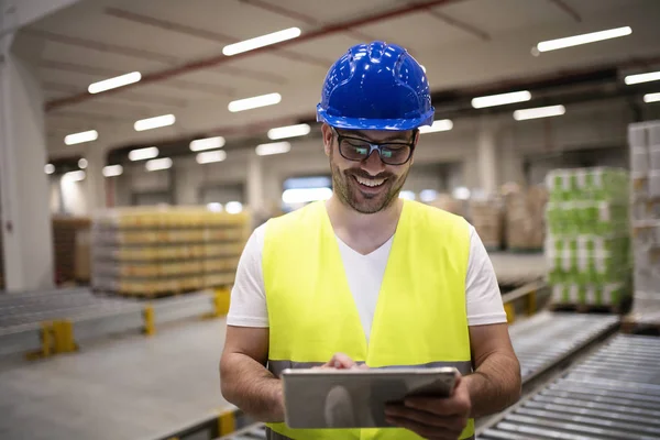 Industriële werknemer in reflecterende jas en HardHat kijken naar tablet in moderne fabriek interieur. — Stockfoto