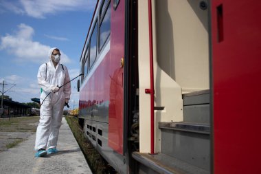 Toplu taşıma sağlık hizmetleri. Beyaz korumalı adam, metroyu dezenfekte edip sterilize ederek yüksek bulaşıcı koronavirüs ya da COVID-19 yayılmasını önlüyor..